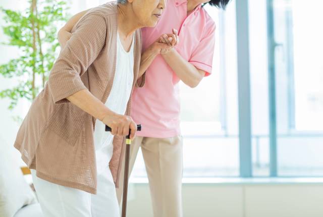 支えられて歩く高齢者